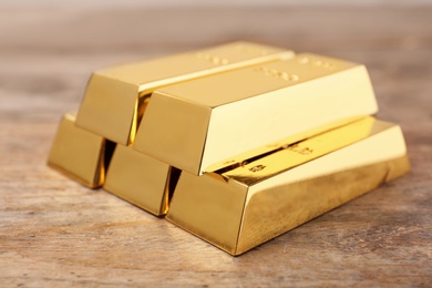 Photo of Precious shiny gold bars on wooden background