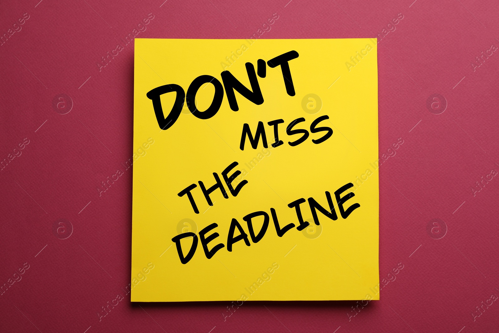 Image of Note with reminder Don't Miss The Deadline on burgundy background