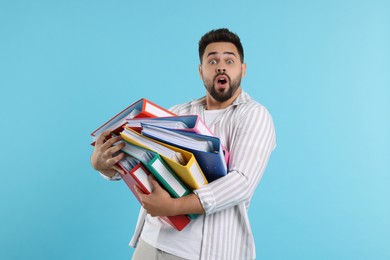 Photo of Shocked man with folders on light blue background