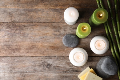 Photo of Spa composition with burning candles on wooden background, flat lay. Space for text