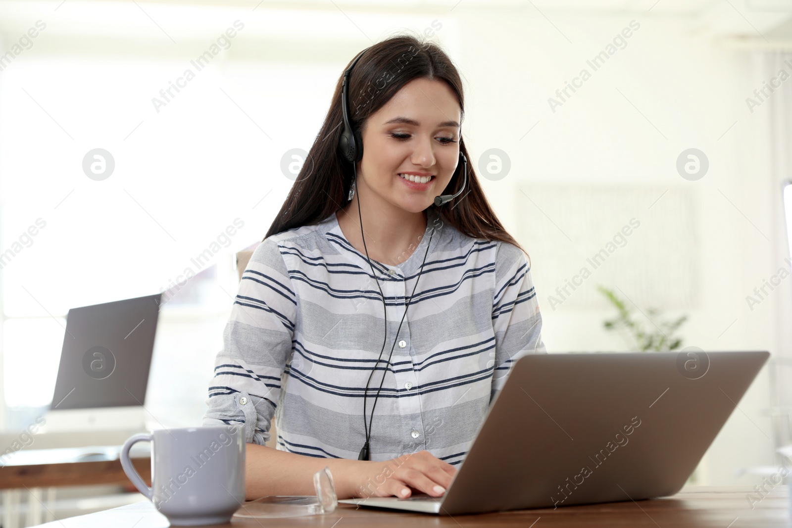 Photo of Young woman using video chat on laptop in home office