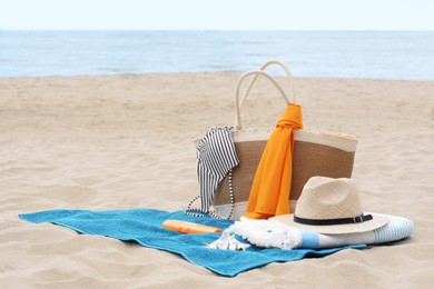 Photo of Blue towel, bag and beach accessories on sandy seashore, space for text