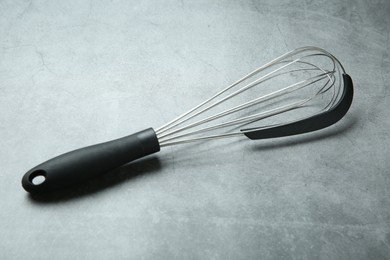 Photo of Metal whisk on gray table. Kitchen tool