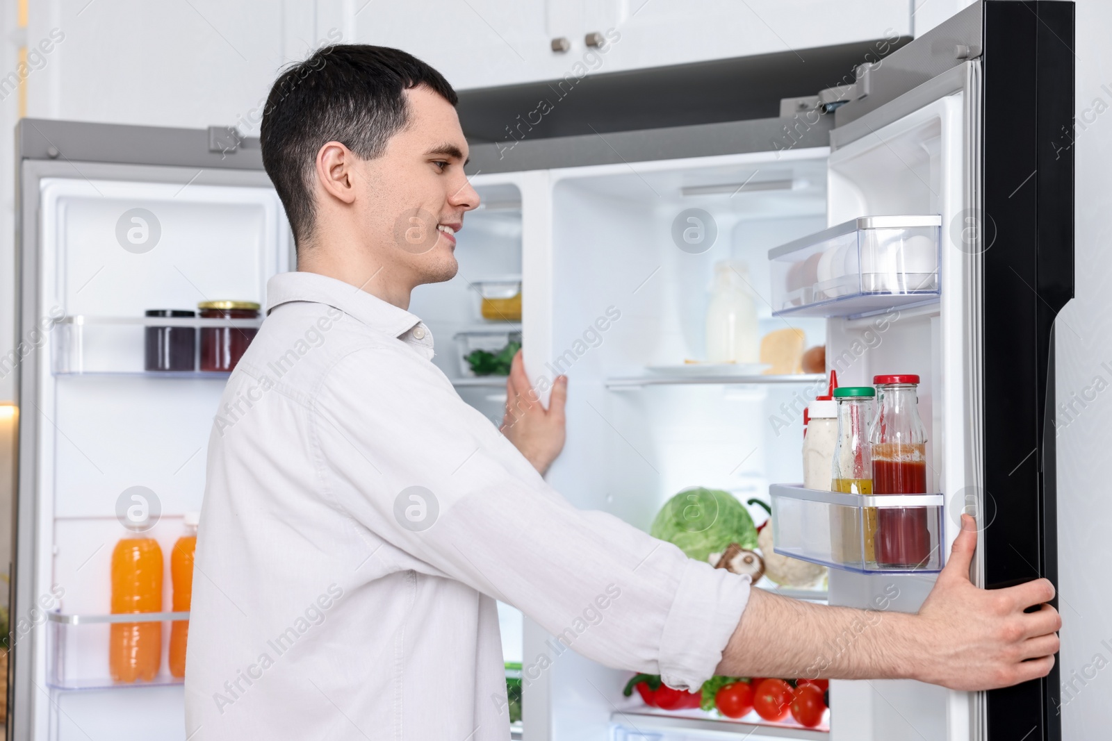 Photo of Happy man near refrigerator in kitchen at home