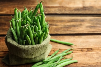 Photo of Fresh green beans on wooden table. Space for text