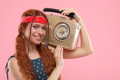 Photo of Stylish young hippie woman with retro radio receiver on pink background