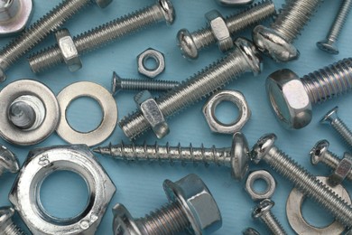 Photo of Many different fasteners on light blue background, flat lay