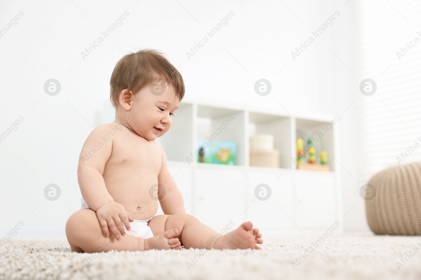 Photo of Cute baby boy sitting on carpet at home, low angle view. Space for text