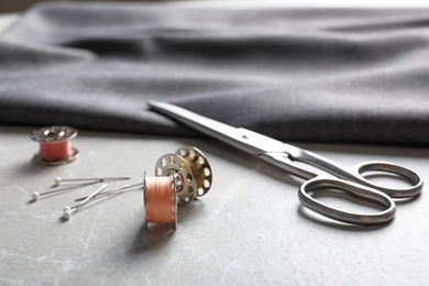 Bobbins with threads, fabric and scissors on table. Tailoring accessories