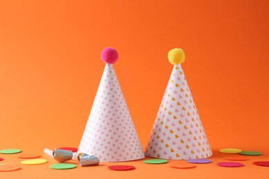 Party hats and other bright decor elements on orange background