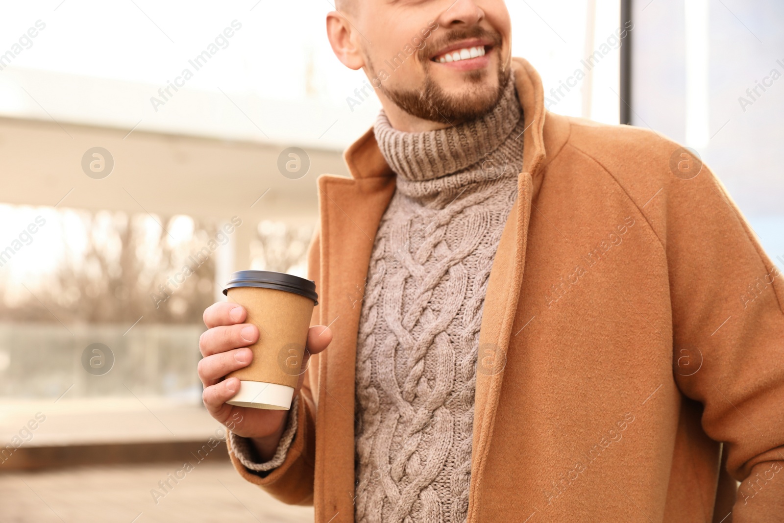 Photo of Man with cup of coffee on city street in morning, closeup