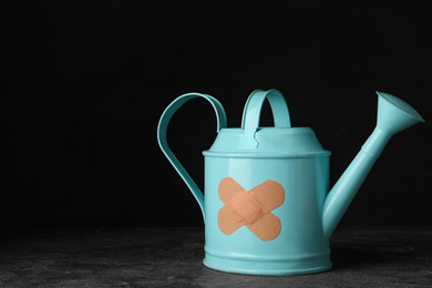 Photo of Light blue watering can with sticking plasters on grey stone table. Space for text