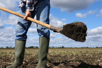 Man digging soil with shovel in field, closeup