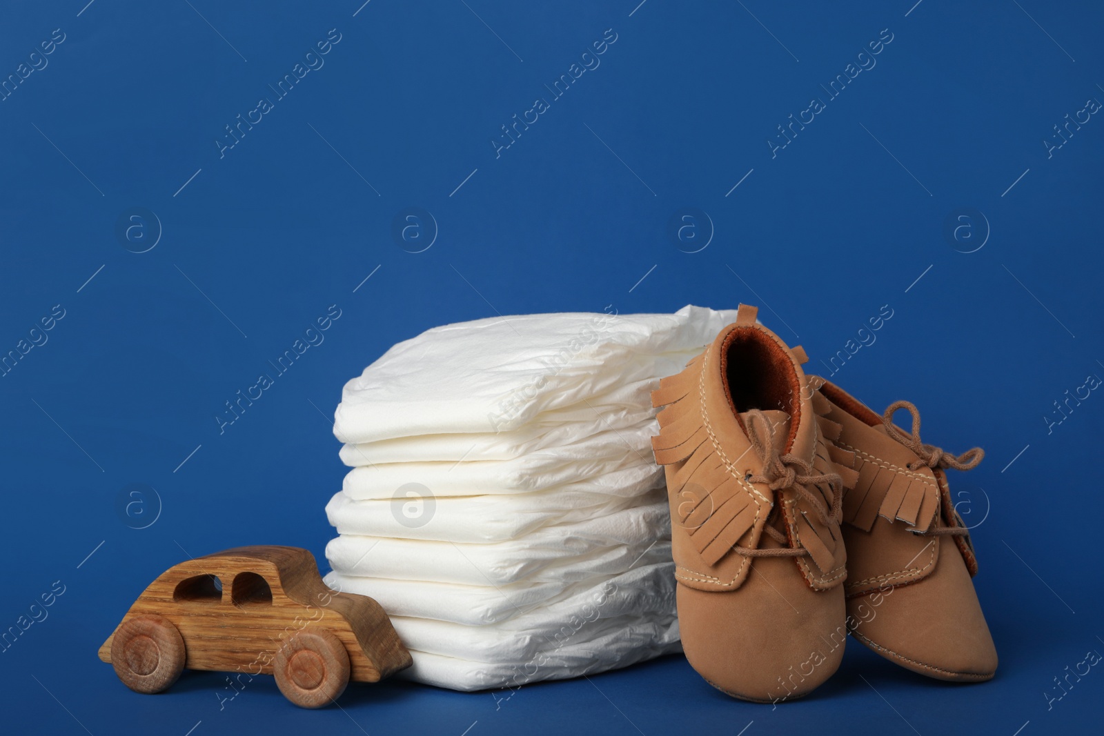 Photo of Diapers, baby accessories and toy car on blue background