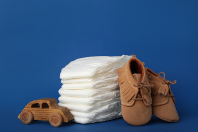 Photo of Diapers, baby accessories and toy car on blue background