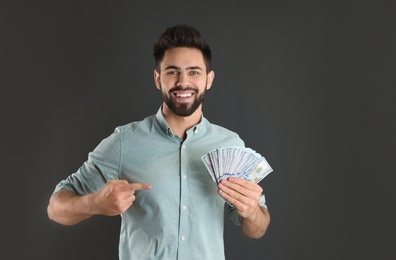 Photo of Portrait of happy young man with money on grey background. Space for text
