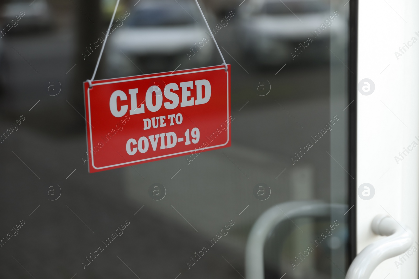 Photo of Red sign with words "Closed Due To Covid-19" hanging on glass door