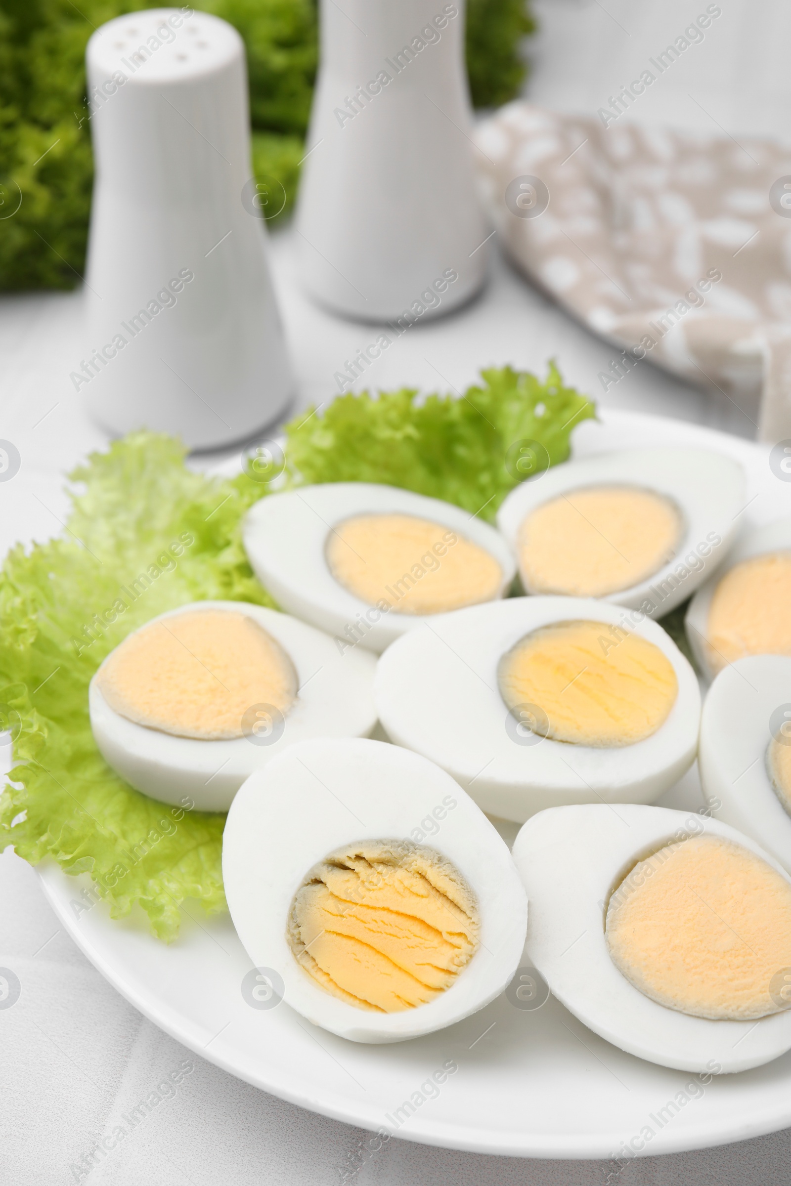 Photo of Fresh hard boiled eggs and lettuce on white tiled table