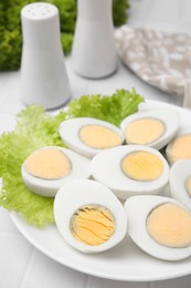 Fresh hard boiled eggs and lettuce on white tiled table