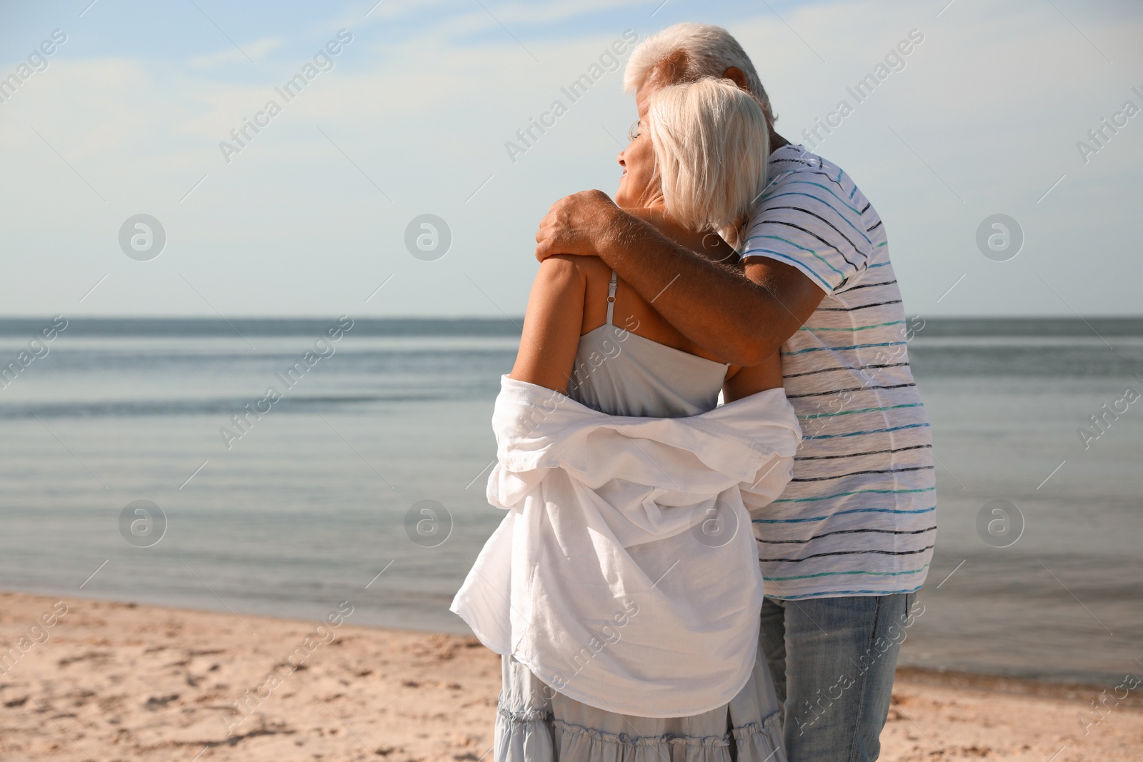 Photo of Mature couple spending time together on sea beach, back view