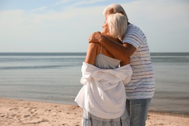 Mature couple spending time together on sea beach, back view