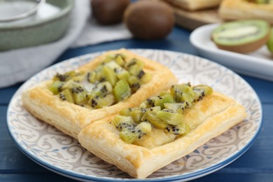 Photo of Fresh tasty puff pastry with kiwi on blue wooden table, closeup