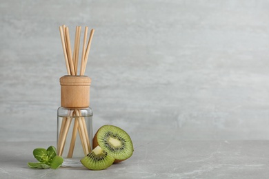 Photo of Aromatic reed freshener and kiwi on table against grey background. Space for text