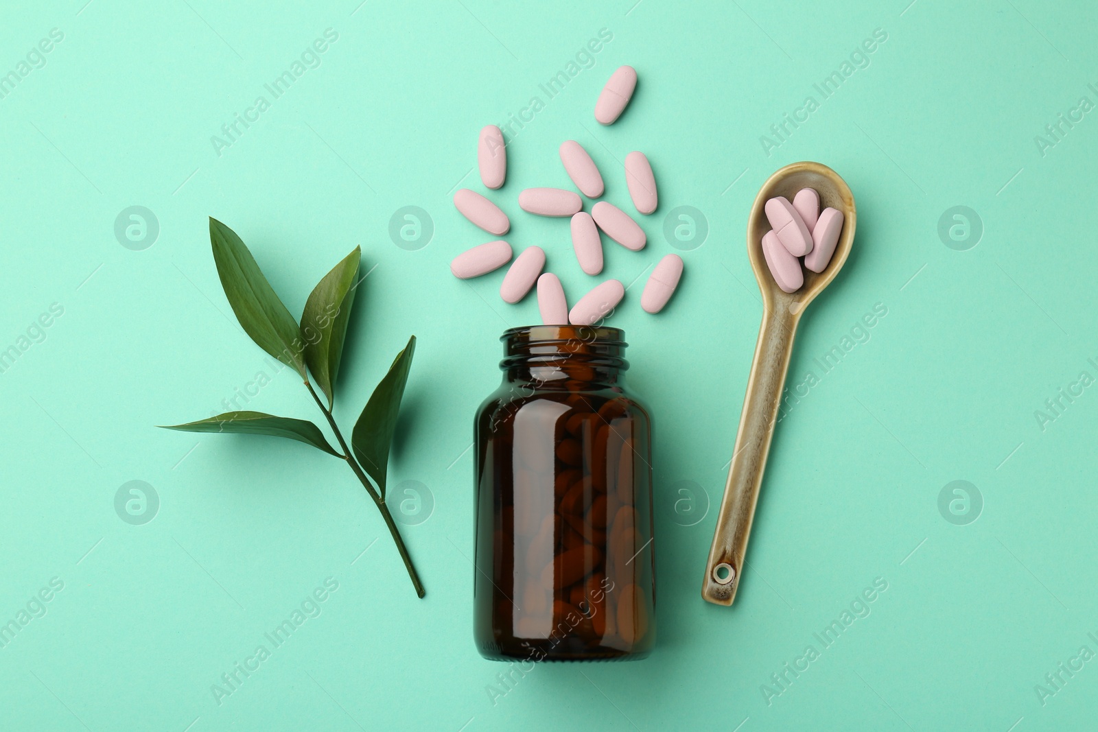 Photo of Vitamin pills, bottle, spoon and branch on mint color background, flat lay