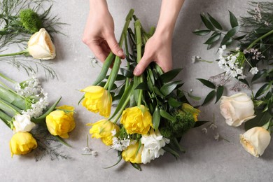 Florist making beautiful bouquet at grey table, top view