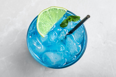 Photo of Tasty Blue Lagoon cocktail on light grey table, top view
