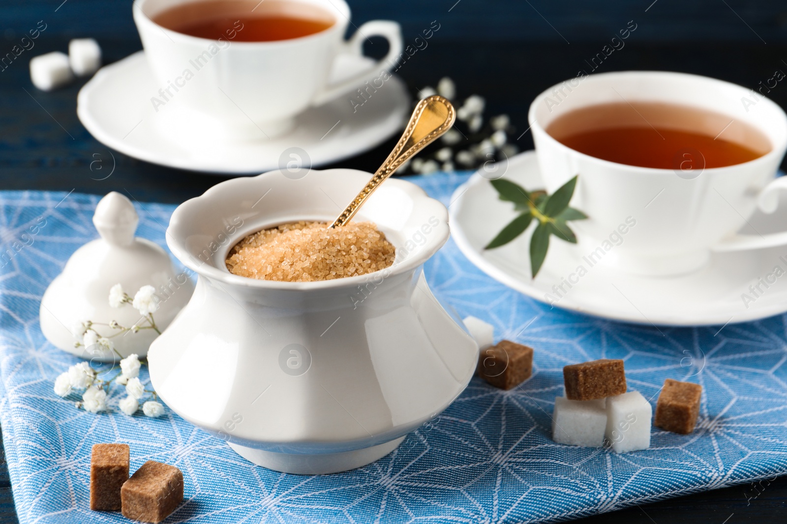 Photo of Ceramic bowl with brown sugar and cups of tea on table