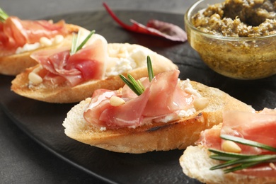 Photo of Tasty bruschettas with prosciutto and cream cheese served on table, closeup