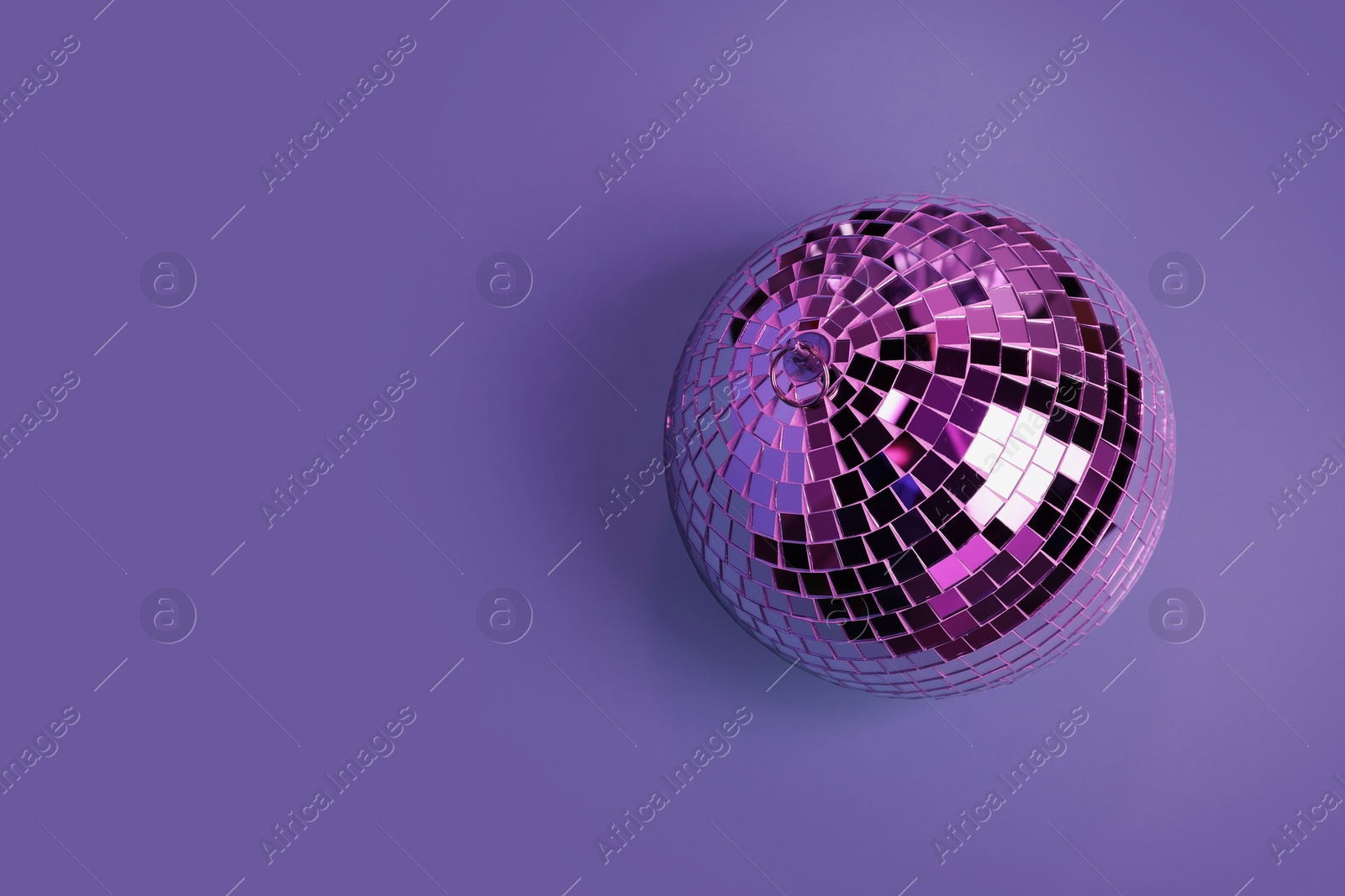 Photo of Shiny disco ball on violet background, top view. Space for text