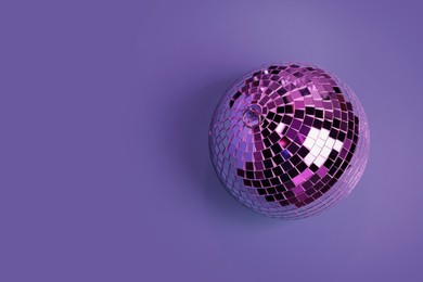 Photo of Shiny disco ball on violet background, top view. Space for text