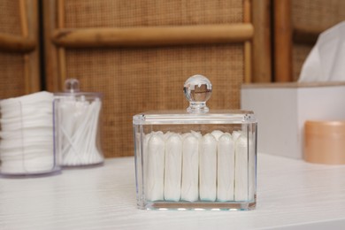 Photo of Glass holder with many tampons on white table. Menstrual hygienic product