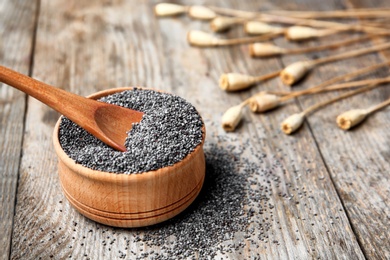 Bowl and spoon with poppy seeds on wooden table