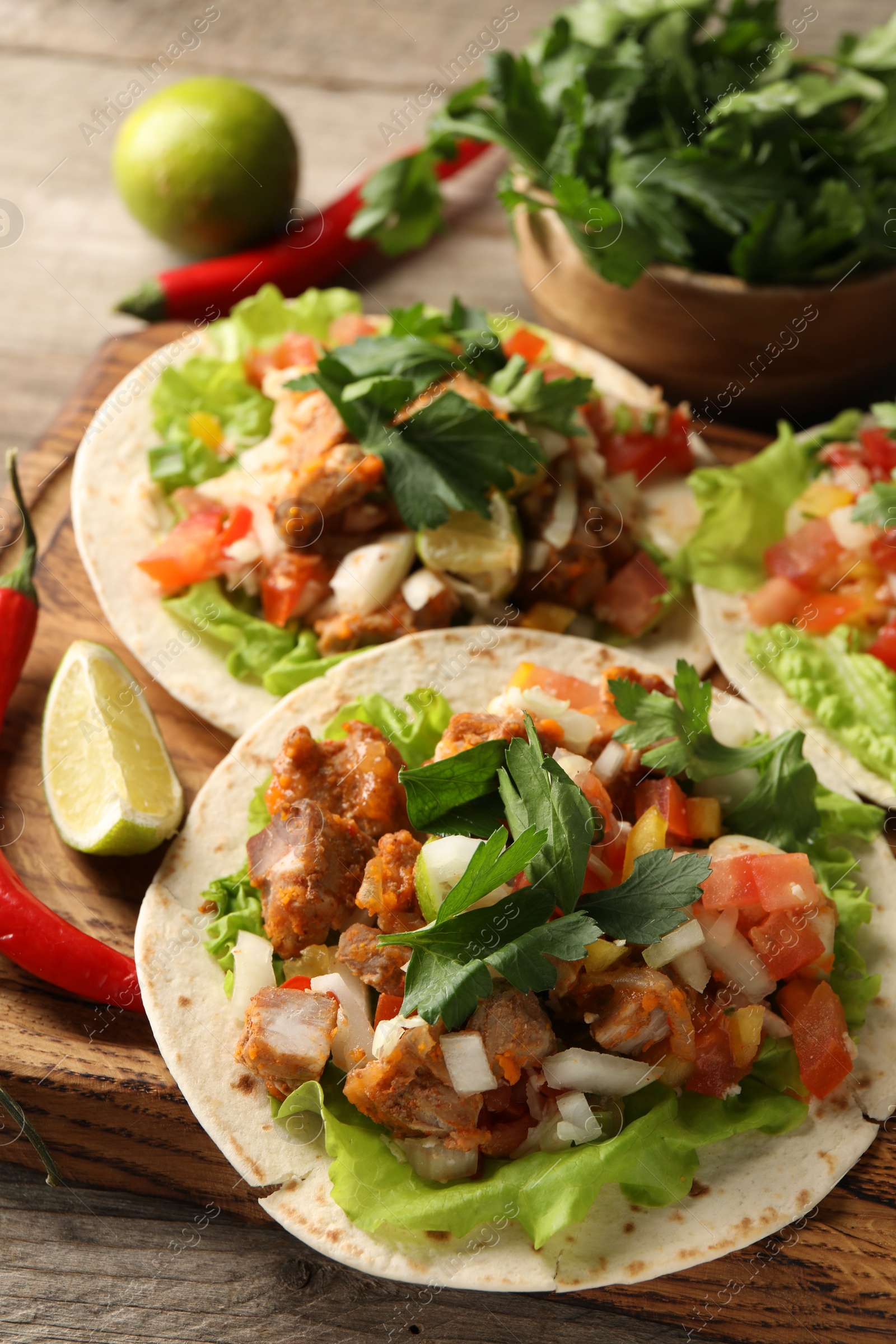 Photo of Delicious tacos with vegetables, meat and lime on table, closeup