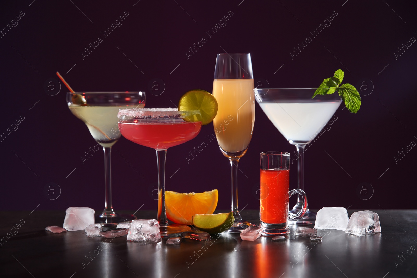 Photo of Many different alcoholic drinks on table against dark background