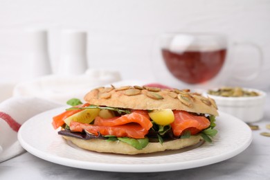 Photo of Tasty bagel with salmon and tomatoes on white marble table, closeup