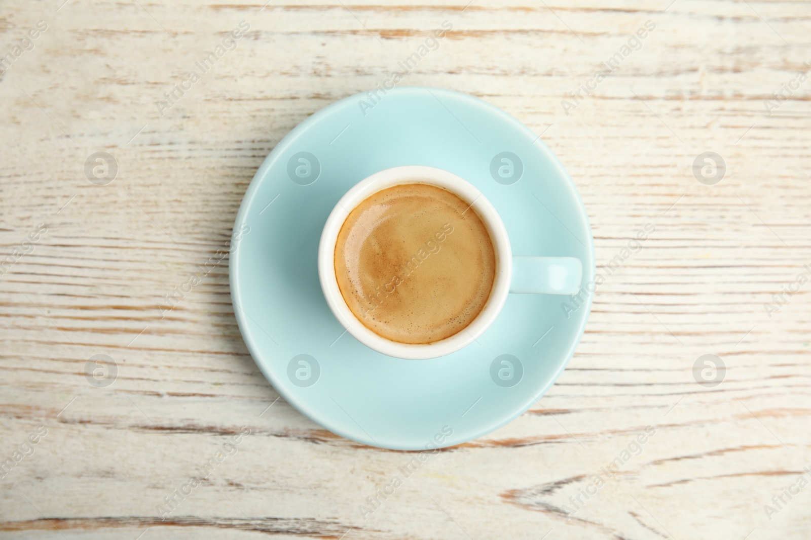 Photo of Cup of tasty coffee on white wooden table, top view