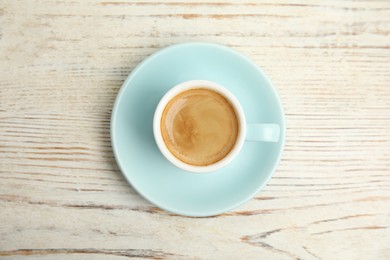 Photo of Cup of tasty coffee on white wooden table, top view