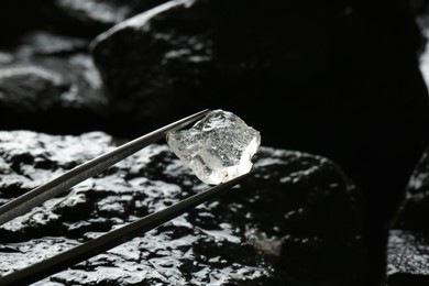 Tweezers with beautiful shiny diamond over stones, closeup