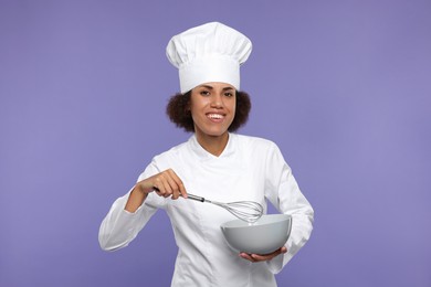 Photo of Happy female chef in uniform with whisk and bowl on purple background