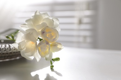 Photo of Beautiful freesia flowers on white table indoors, closeup. Space for text