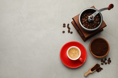 Flat lay composition with coffee grounds and roasted beans on light table, space for text