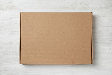 Photo of Cardboard box on white wooden background, top view