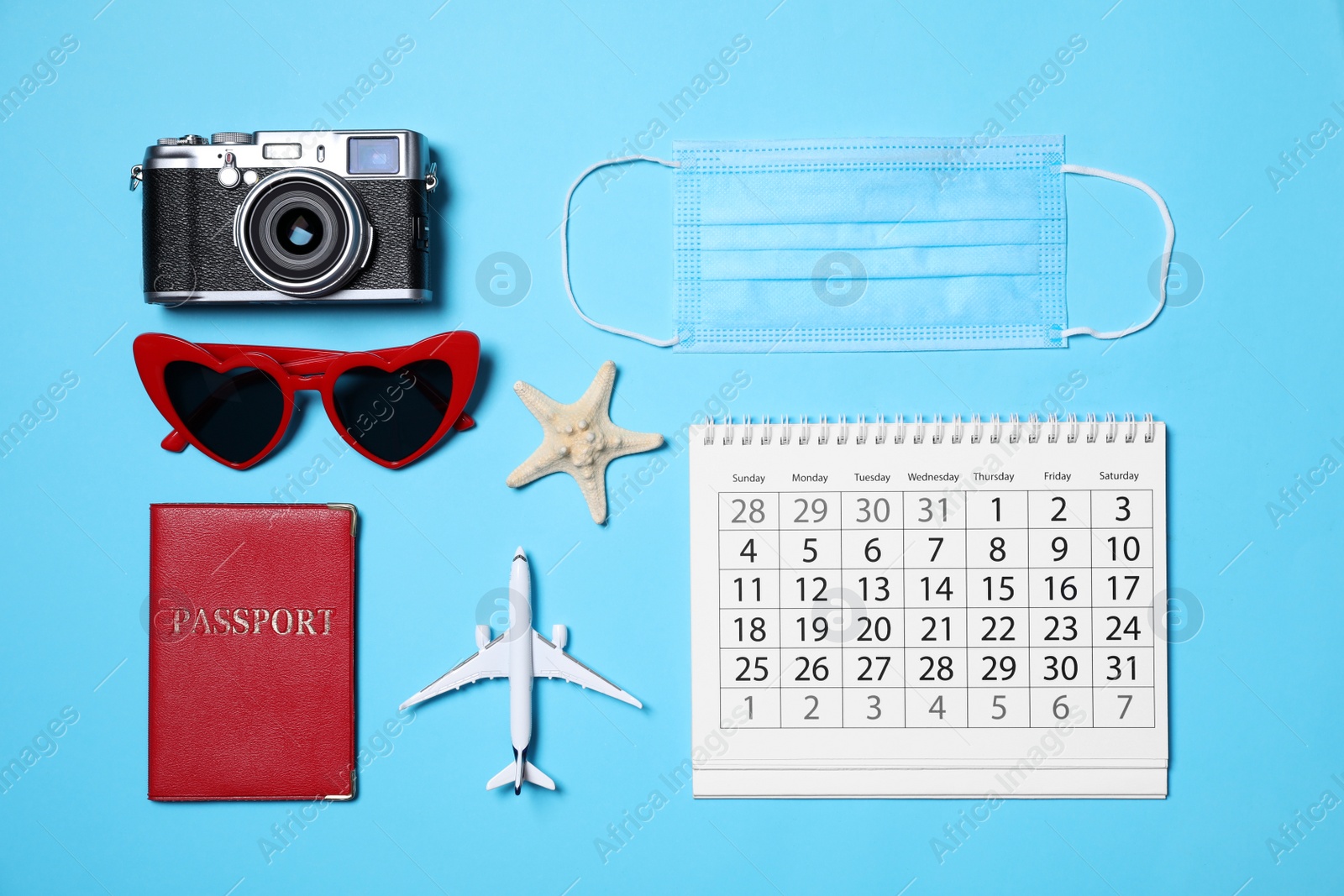 Photo of Flat lay composition with passport, protective mask and calendar on light blue background