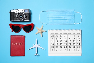 Photo of Flat lay composition with passport, protective mask and calendar on light blue background