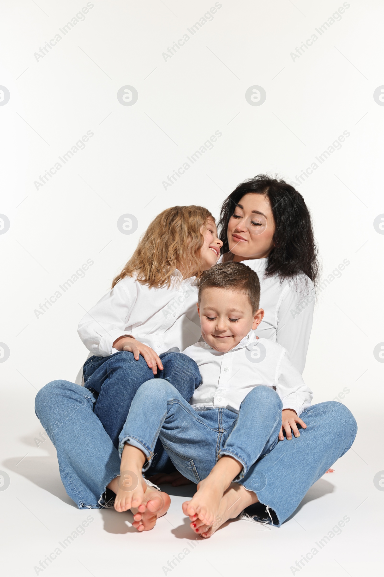 Photo of Little children with their mother sitting together on white background