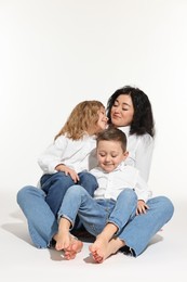Photo of Little children with their mother sitting together on white background